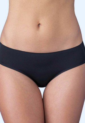 Damski tors pokazujący środkową część ciała i górne partie ud, ubrany w proste czarne majtki bikini na jasnym tle.