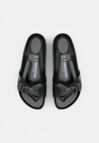 Paire de sandales noires Birkenstock slip-on avec une seule bride à boucle réglable, semelles moulées et marquage taille 37 à l'intérieur.
