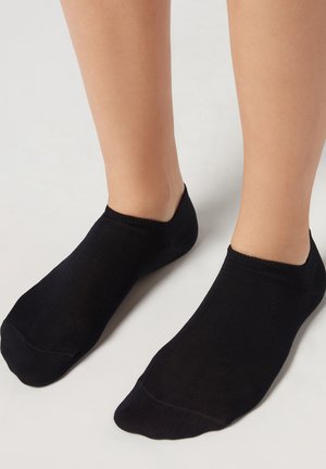 Sorte ankelstrømper lavet af et blødt, strækbart strikmateriale med en sømløs tå og ribbede manchetter, der har en glat tekstur og et minimalistisk design.