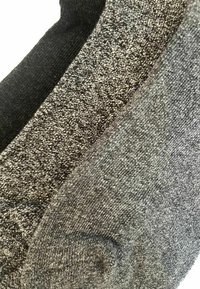Zwei Socken, eine schwarze und eine dunkelgraue, aus strukturiertem Strickmaterial mit einem dezenten gesprenkelten Muster und verstärkten Fersen. 