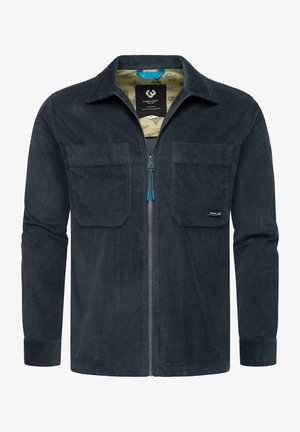 Dark navy corduroy shirt jacket with a zip front, two chest pockets, and a patterned inner lining. Features blue zipper accents.