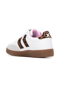 Las zapatillas blancas presentan detalles de estampado de leopardo marrón en los laterales, un forro interior rosa y una suela de goma marrón texturizada.