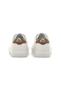 Zapatillas blancas de cuero con una textura suave, que presentan un acento marrón en el talón y un logo circular. Suela de goma plana y abertura acolchada.