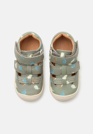 Kindergroene sandalen met blauwe en beige walvispatronen, gevoerde binnenkant en twee verstelbare klittenbandriemen op witte zolen.