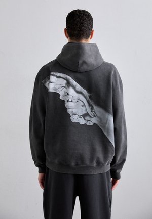 Mörkgrå sweatshirt med en stor monokrom handgrafik på baksidan. Mjuk tyg, huva design, ribbade ärmslut och fåll. Avslappnad passform.