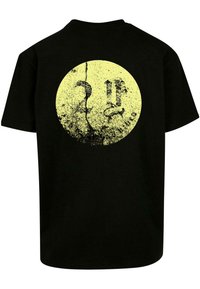 Černé bavlněné tričko s velkým žlutým kruhovým grafickým prvkem s opotřebovanou texturou, zobrazující stylizovanou tvář a čísla 2 a 11.