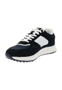 Zapatilla deportiva para hombre en blanco y negro con parte superior de malla y ante, cordones blancos y suela gruesa de goma, mostrada en ángulo para exhibir detalles frontales y laterales.