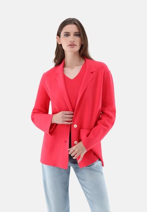 Blazer fucsia brillante realizzato in tessuto liscio, con revers a punta, chiusura con un solo bottone e tasca frontale. Abbinato a un top a costine.