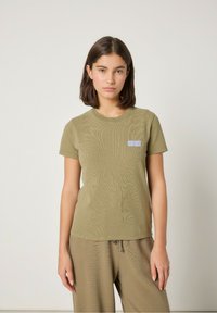 Olivovozelené tričko s krátkym rukávom vyrobené z textúrneho materiálu, s malým bielym logom "AMERICAN VINTAGE" na ľavej hrudi.