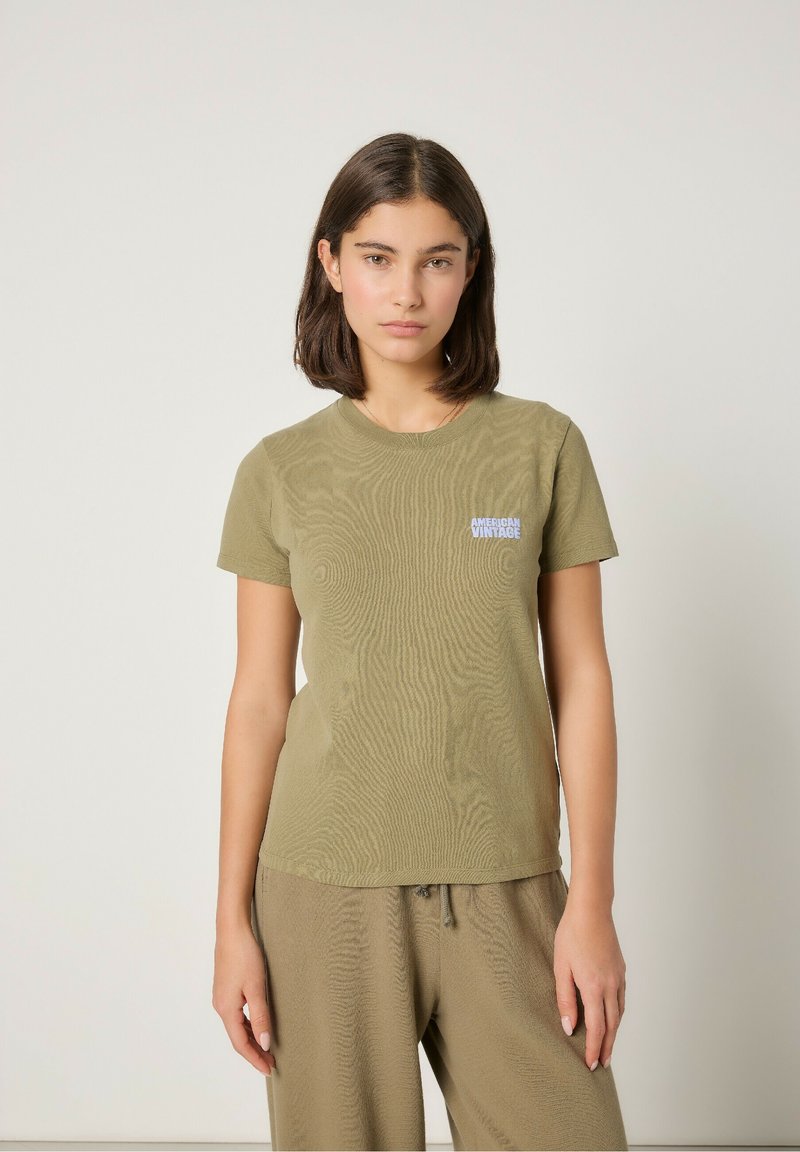 Olivovozelené tričko s krátkym rukávom vyrobené z textúrneho materiálu, s malým bielym logom "AMERICAN VINTAGE" na ľavej hrudi.