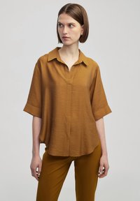 Bruine korte mouwen overhemd met een kraag, voorzien van een subtiele textuur en een halve knopenrij, gecombineerd met bijpassende bruine broek.