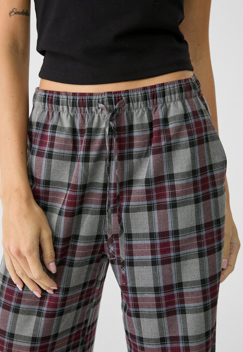 Pizamy w kratę w odcieniach szarości, czerni i burgundowym. Elastyczny pas z sznurkiem do regulacji. Wykonane z miękkiego materiału, z wzorem w kratę.