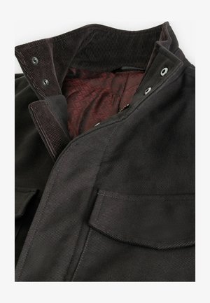 Jachetă din catifea neagră cu o căptușeală matlasată de culoare burgundă. Dispune de închideri cu capse și două buzunare frontale pentru utilitate și design.