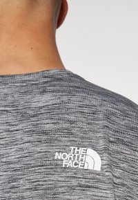 Halli melange T-särk ümarate kraejoontega, millel on vasakul õlal valge logo märk "The North Face". Pehme, tekstuuriga kangas.