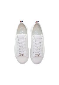 Bílé tenisky s texturovaným textilním svrškem, zaoblenou špičkou, plochými tkaničkami a kovovým logem. Obsahují červené a modré poutka na patě.