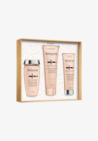Il set Kérastase Curl Manifesto include tre prodotti in confezione rosa con dettagli argentati, presentati in una scatola con macchie dorate.