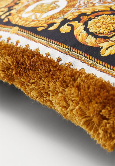 Textured decorative cushion with a black and gold ornate pattern, featuring a plush golden fringe along the edge and a smooth surface.