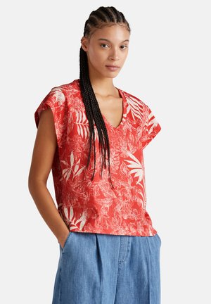 Haut à impression florale rouge avec un décolleté en V, des manches courtes et une coupe décontractée, assorti à un pantalon bleu ample. Texture de tissu douce.