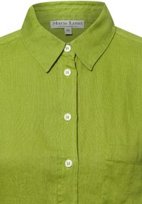 Green linen shirt with a pointed collar, featuring white buttons and a chest pocket. Textured fabric with a smooth finish. Size label visible.