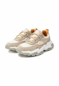 Zapatillas beige con materiales de malla y ante, suela blanca gruesa, acentos naranjas en contraste y diseño de cordones con cuello acolchado.