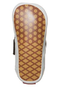 Suela de un zapato blanco para bebé con un patrón de piedras hexagonales y diamantes de color marrón para mayor agarre y estabilidad.