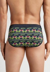 Męskie ciemnoniebieskie slipy z powtarzającym się wzorem Grincha, w zielonych i czerwonych kolorach, elastycznym pasem oraz dopasowanym krojem.