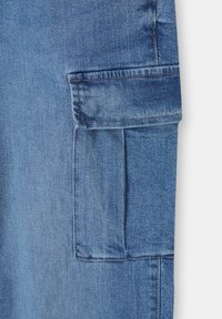 Tissu en denim bleu avec une poche plaquée rectangulaire dotée d'un rabat et des coutures visibles le long des bords.