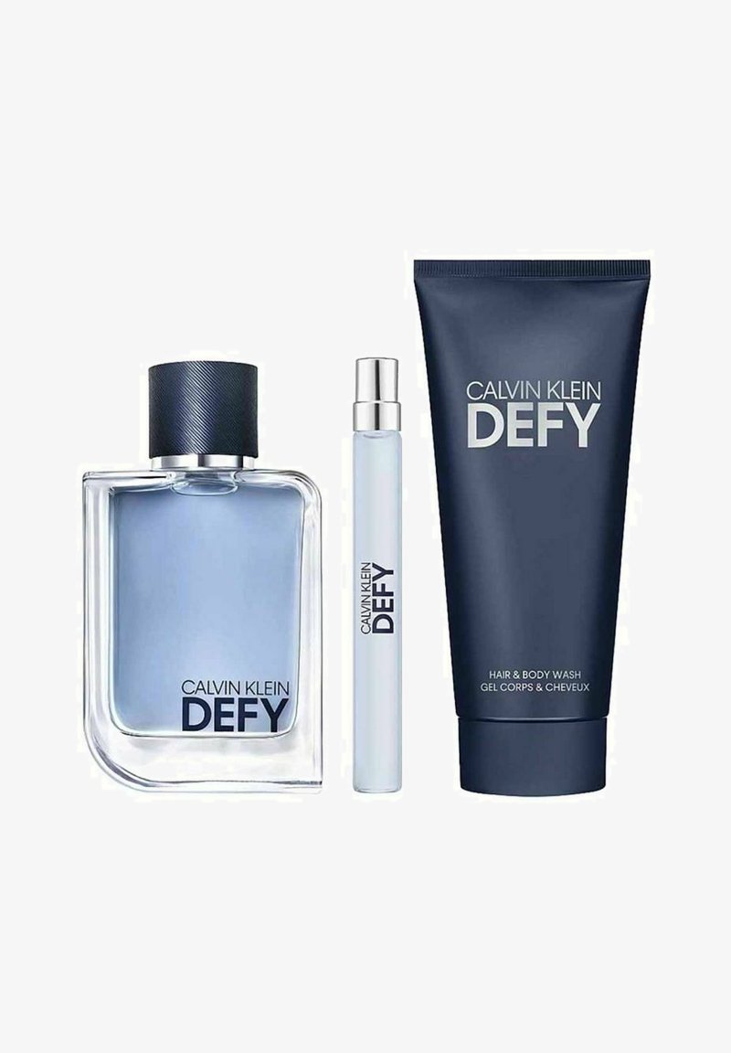 Calvin Klein Defy tuoksusarja: lasipullo, jossa on sinistä nestettä ja tumma korkki, rullapullo sekä tummansininen putki hius- ja vartalopesua varten, kaikki merkitty.
