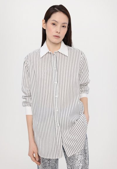 Witte button-up shirt met zwarte verticale strepen, met een puntige kraag, lange mouwen en een relaxte pasvorm met zijsplitten.