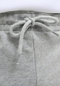 Grå bomulds sweatsbukser med en tekstureret stof, der har en snor i taljen og detaljer i sidesømmen.