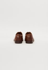 Brune lærdress sko med en glatt overflate, rund tå og en lav stablet hæl. Har minimalt med sømmer og et elegant design.
