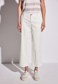 Wide-leg, off-white cotton pants with a smooth texture, featuring a button closure, side pockets, and subtle creases for detail.