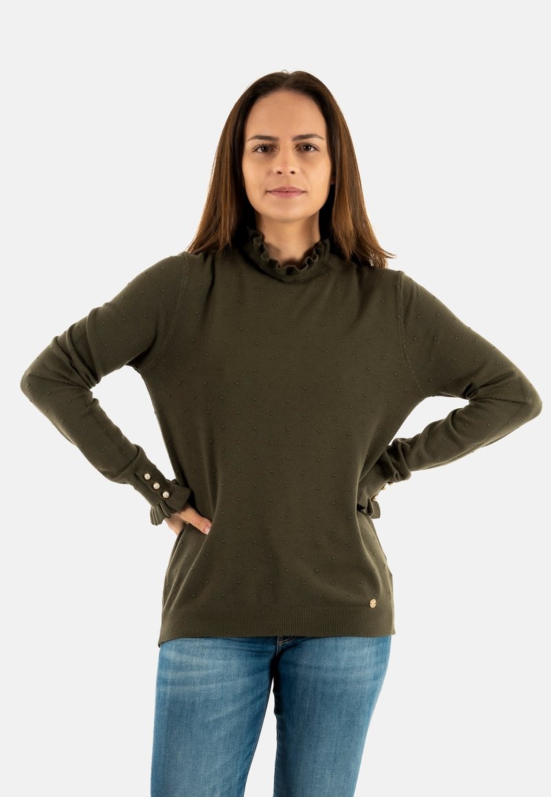 Maglione verde oliva con collo a volant, motivo a pallini testurizzato e polsini con bottoni. Abbinato a jeans blu.