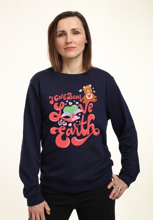 Mørkeblå sweatshirt med et farverigt "I Care Bear" grafik, der viser en bjørn, hjerter og teksten "Love the Earth". Blødt stof, afslappet pasform.
