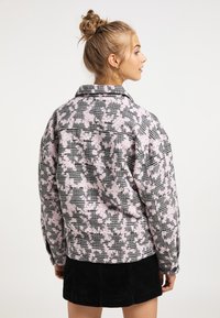 Giacca oversize in motivo scozzese rosa e nero, con collo a camicia e polsini con bottoni, realizzata in tessuto texturizzato.