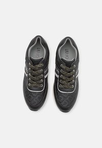 Schwarze Sneakers mit einem strukturierten Design, metallisch goldenen Schnürsenkeln und weißen Akzenten. Gepolsterte Knöchelunterstützung und graue Innenauskleidung. Runde Zehenform.