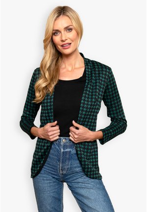 Black and teal houndstooth blazer with long sleeves, open front, and a fitted shape, paired with a black top and high-waisted jeans.