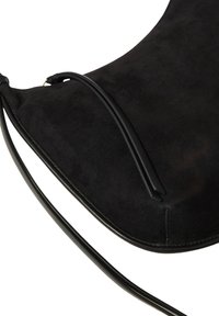 Black suede handbag with thin black leather shoulder strap and simple design, shown against white background.