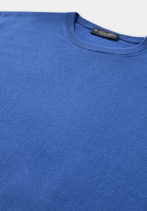 Modrý pletený svetr s kulatým výstřihem. Má hladkou texturu a proužkované okraje. Etiketa viditelná na výstřihu.