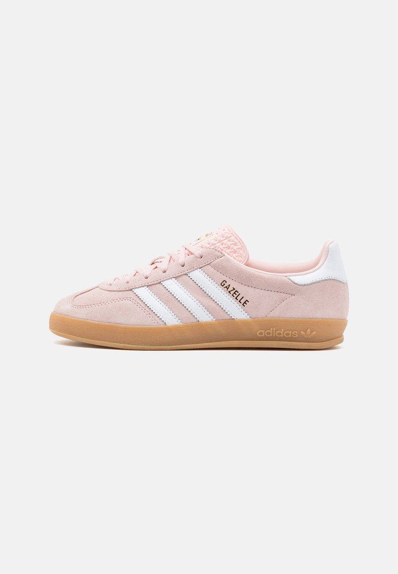 Sneaker in suede rosa con dettagli in pelle bianca e tre righe bianche. Presenta una suola in gomma color cuoio e un marchio impresso sulla linguetta.