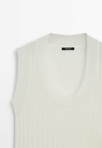 Veste en tricot blanc sans manches à côtes avec un col rond et une étiquette noire "Massimo Dutti" à l'intérieur du col.