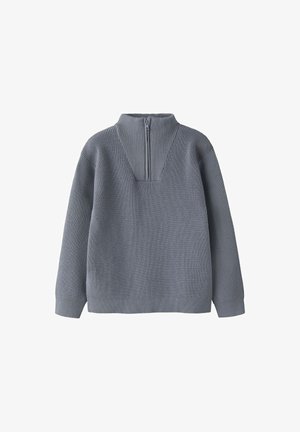 Pelēks adīts džemperis ar garām piedurknēm, ribotu augstu apkakli un priekšējo rāvējslēdzēju, kas stiepjas līdz pusei krūtīm.