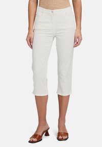 Pantalons blancs coupés avec un design ajusté, fabriqués dans un tissu lisse. Comprend une fermeture à bouton à l'avant et deux poches latérales.