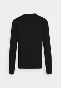 T-shirt noir à manches longues avec col rond, vu de dos avec un ourlet droit et des poignets côtelés sur un fond clair uni.
