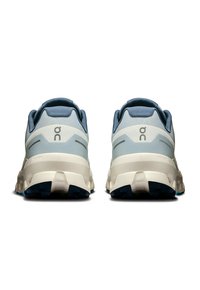 Light blue and cream running shoes with a textured midsole and rubber outsole. Features a minimalist design and logo on the heel.