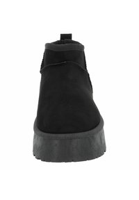 Botas de cuero ante negras hasta el tobillo con una suela de plataforma texturizada. Presenta paneles laterales elásticos y una lengüeta en el talón para facilitar su uso.
