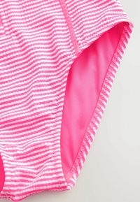 Ružové pruhované plavky vyrobené z hladkej, elastickej látky. Majú úzke biele vodorovné pruhy a jednofarebný ružový interiér. Viditeľné švy.