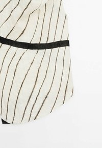 Tissu à motifs noir et blanc présentant des lignes diagonales et une bande horizontale noire. Texture douce avec une forme drapée.