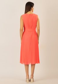 Korallenfarbenes Faltenkleid mit tailliertem Bund, ärmellosem Design und knielanger Länge. Mit einem Reißverschluss hinten und glattem, leichtem Stoff.