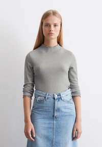 Grijze geribde langetermijntop met een golfvormige halslijn, gecombineerd met een lichtblauwe spijkerrok met hoge taille. Glad textuur, aansluitend ontwerp.